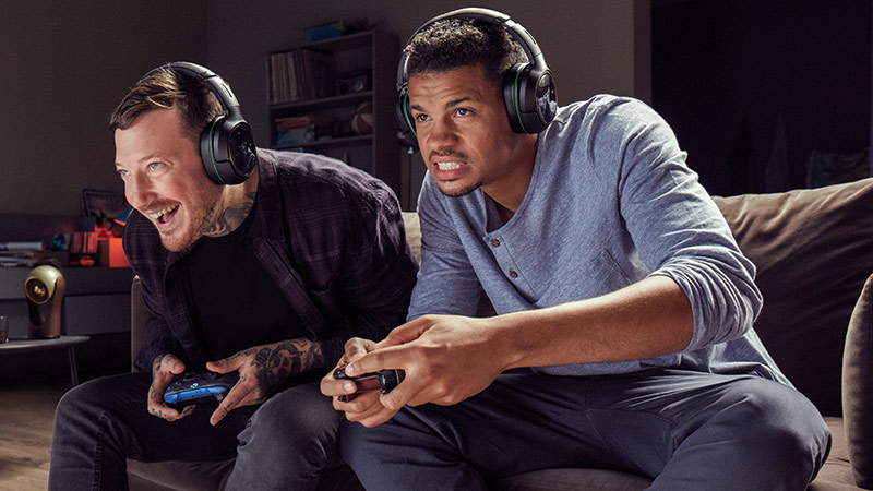 Two people on a couch wearing headsets and playing Xbox